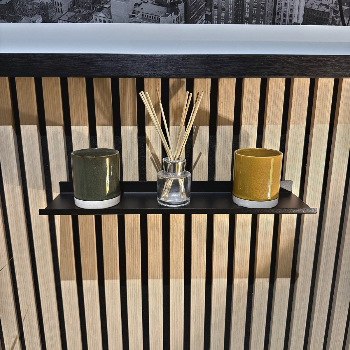 Matt black slat wall shelf on an oak acoustic slat wall