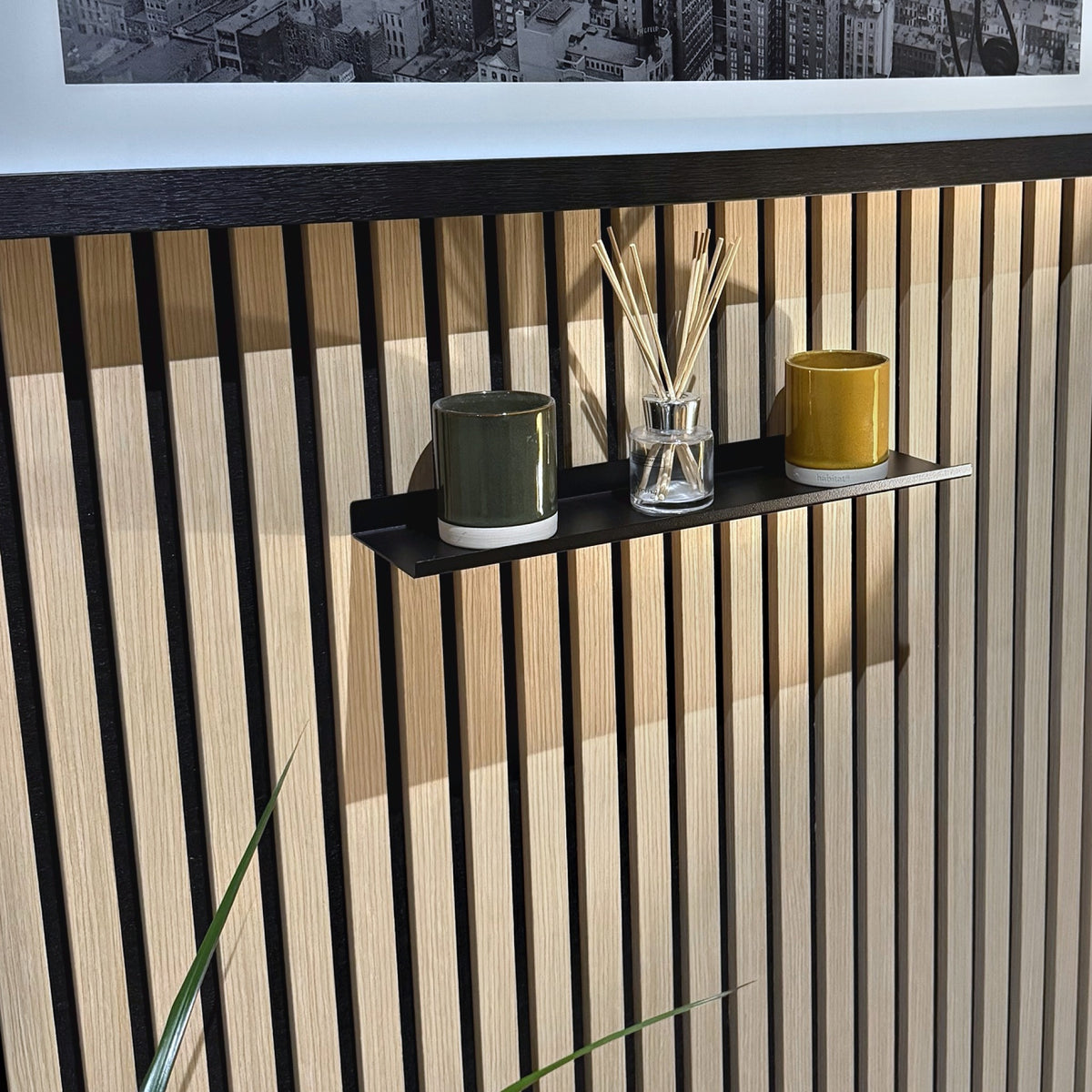 Slat wall shelf styled below a framed print